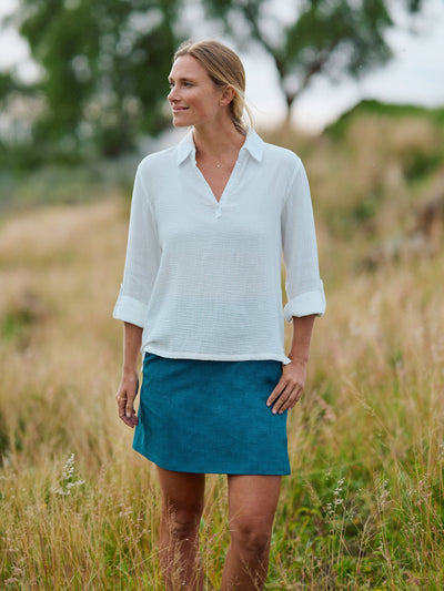 Woman wearing a white shirt and blue RipSkirt skirt standing in a field front view